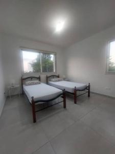 two beds in a white room with two windows at Luxury 2 bedroom apartment in Larnaka