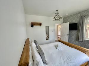 a bedroom with a large white bed with a chandelier at Rodgers Land (The Bungalow) in Boston