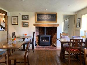 a dining room with tables and a fireplace in a restaurant at the Cartwheel Inn in Whitsbury +1 photo