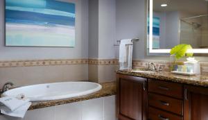a bathroom with a tub and a sink and a mirror at Naples Bay Resort and Marina in Naples