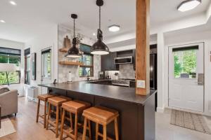une cuisine avec un grand comptoir noir et des tabourets dans l'établissement Tremblant Prestige - Les Eaux 223-4, à Mont-Tremblant