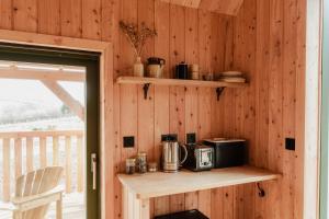 a room with a wooden wall with a counter with a microwave at The Bulls Head Wild Cabins in Hereford