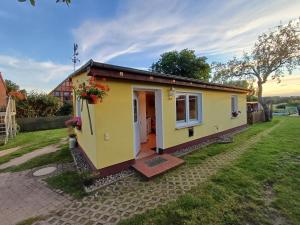 ein kleines gelbes winziges Haus in einem Hof in der Unterkunft Ferienbungalow Jahnke auf Usedom mit Wlan in Zirchow