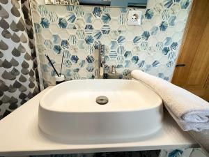 a white sink in a bathroom with blue and white tiles at Golden Escape - Charming Studio in Prime Location in Craiova +12 photos