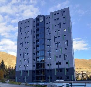 een hoog grijs gebouw met bergen op de achtergrond bij A due passi dal cielo in Passo del Tonale