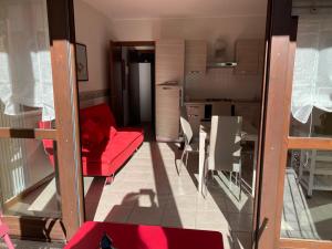 a living room with a red couch and a kitchen at Mimosa in Acquaseria