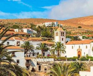 a large white building with palm trees and a hill at Apartamento Joshualba II in Mesquer