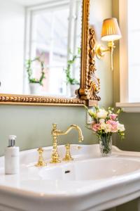 a bathroom sink with a mirror and a vase of flowers at Dyvig Badehotel in Nordborg +79 photos