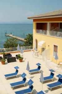 a patio with blue and white chairs and the ocean at Hotel Vela D'oro ***S in Bardolino