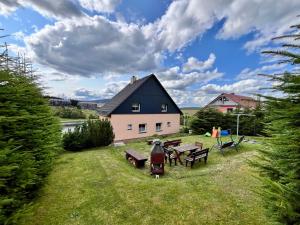 a house with a picnic table and benches in the grass at Apartmány Happy Klínovec in Loučná pod Klínovcem