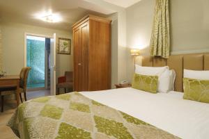 a hotel room with a bed and a desk and a window at Fanhams Hall, Exclusive Collection in Ware