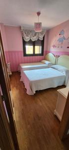 two beds in a room with pink walls at Piso céntrico al lado de Oviedo in Lugones