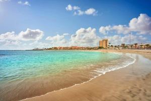 a beach with turquoise water and buildings in the background at Villa Casablanca by Welcome Tenerife in Chayofa