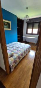 a bedroom with a bed in a room with blue walls at Piso céntrico al lado de Oviedo in Lugones +3 photos