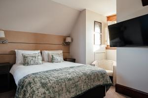 a bedroom with a large bed and a television at Fanhams Hall, Exclusive Collection in Ware