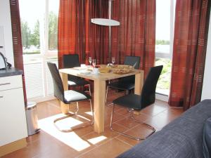 een eettafel met zwarte stoelen en een tafel met wijnglazen bij Meerblick 9 - Großenbrode in Großenbrode