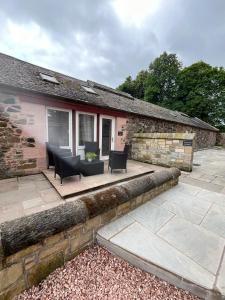 a house with a patio with two chairs and a table at Stewards Bothy in Cornhill-on-tweed