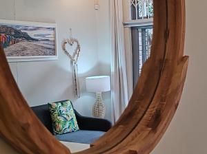 espejo en una habitación con silla y lámpara en Coastal Studio Empire Apartment, en Muizenberg
