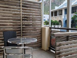 una mesa y sillas en un balcón con una pared de madera en Coastal Studio Empire Apartment, en Muizenberg