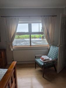 Habitación con silla y ventana grande. en Clare House Bed & Breakfast, en Ballycastle
