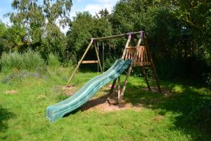 a playground with a slide in the grass at Villa Marie-Louise in NÃ©ron