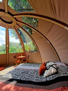 a room with a bed in a tent with windows at Les nuits de Cassiopee in Sorde-lʼAbbaye