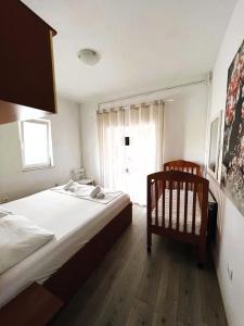 a bedroom with a bed and a crib and a window at Family Apartments K&M in Pag
