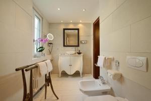 a white bathroom with a sink and a toilet at Monte Rosa Boutique Hotel in Zermatt +32 photos
