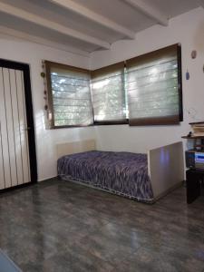 a bedroom with a bed and two windows at Casa en Villa Los Aromos cerca del río in Villa Los Aromos
