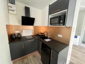 a kitchen with a black counter top and a microwave at Appartement Romantique - 044 in Rouen