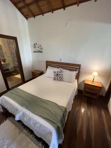 a bedroom with a bed and a lamp on a table at Chalés Renovo Visconde de Mauá in Visconde De Maua