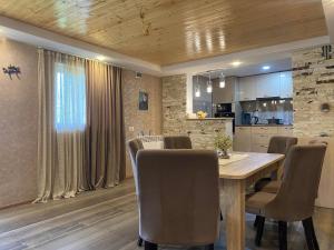 a kitchen and dining room with a wooden table and chairs at Nicolas GuestHouse in Kʼolashi