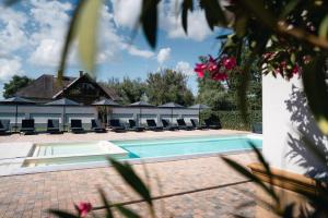 a swimming pool with chairs and a building at Hunor Hotel és Étterem in Vásárosnamény