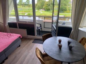 una stanza con un tavolo, un letto e una finestra di Wetterwillefriesland a Wommels Altre 24 foto