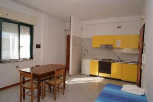 モンテジルヴァーノにあるResidence Club le Nazioniの木製テーブルと黄色のキャビネット付きのキッチン