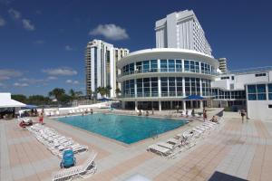 Una piscina frente a un edificio con sillas y gente. en Miami Beach Apartments by MiaRentals, en Miami Beach