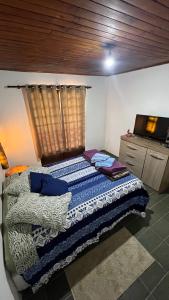 a bedroom with a bed and a dresser at Lar doce lar da Neuza in Campos do Jordão