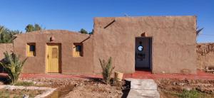 un pequeño edificio con una puerta en el desierto en Dar Tiniri - Guest House, en Arhla Ou Drar