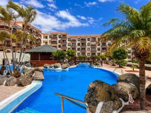 a pool at the resort with palm trees and buildings at Seaside apartment with a sea view in Costa Del Silencio