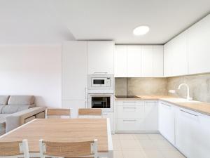 a kitchen with white cabinets and a wooden table at Seaside apartment with a sea view in Costa Del Silencio