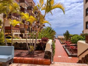 a balcony with palm trees and a building at Seaside apartment with a sea view in Costa Del Silencio