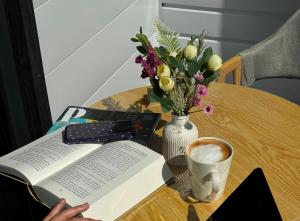 a table with a book and a vase of flowers and a cup of coffee at Nomads Home in Bishkek