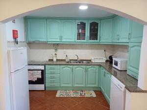 a kitchen with green cabinets and a white refrigerator at Casa do Poço in Quinta do Anjo