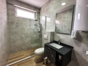 a bathroom with a shower and a toilet and a sink at Grand Apartments Prishtina in Pristina