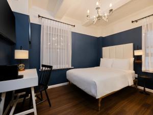 a bedroom with blue walls and a bed and a desk at voco The Franklin New York by IHG in New York