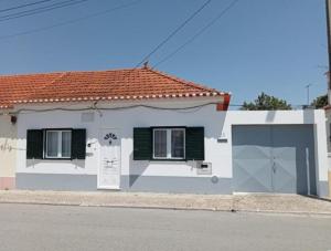 a white house with green shutters and a garage at Casa do Poço in Quinta do Anjo