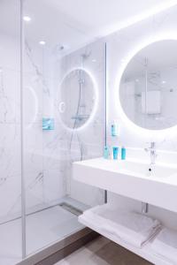 a white bathroom with a sink and a mirror at Novotel Montpellier in Montpellier