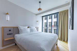 a white bedroom with a large bed and a window at Quartier Libre Opera in Paris
