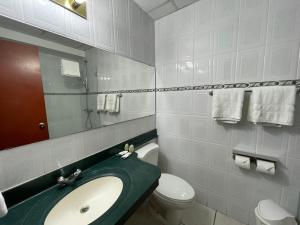 a bathroom with a sink and a toilet and a mirror at Hotel Gardenia Inn in San Salvador
