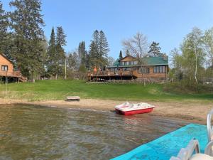 a red boat in the water in front of a house at Sure Game Wilderness Resort in Wirt